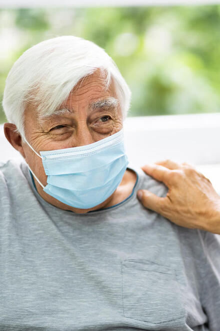 Ein älterer Mann mit einer medizinischen Atemmaske.