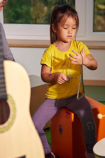 Man sieht eine Gitarre, im Hintergrund sitzt ein Kind