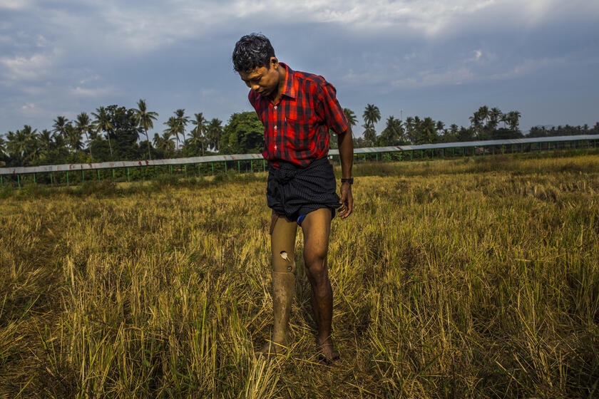Ko Min Min mit Beinprothese steht auf einem Feld.