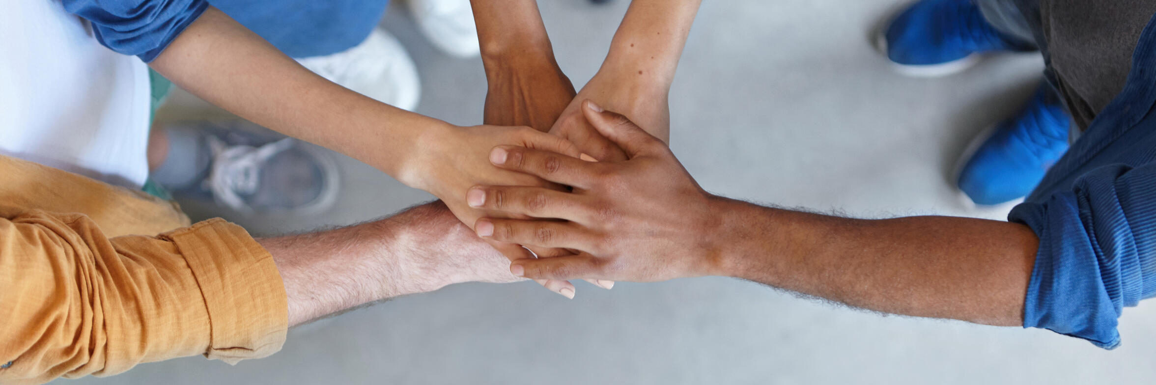 Mehrere Menschen legen ihre Hände übereinander und zeigen damit Teamgeist und Zusammenhalt.