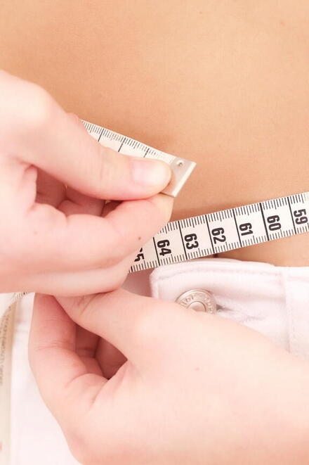 Frau die mit Maßband ihren Bauchumfang misst