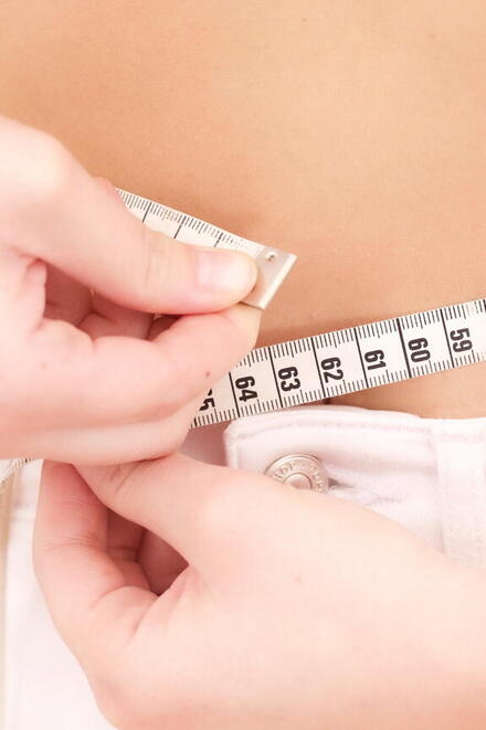 Frau die mit Maßband ihren Bauchumfang misst
