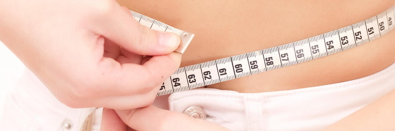 Frau die mit Maßband ihren Bauchumfang misst