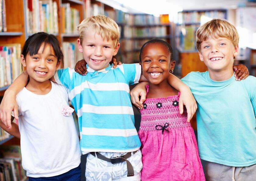 Vier lächelnde Kinder stehen nebeneinander.
