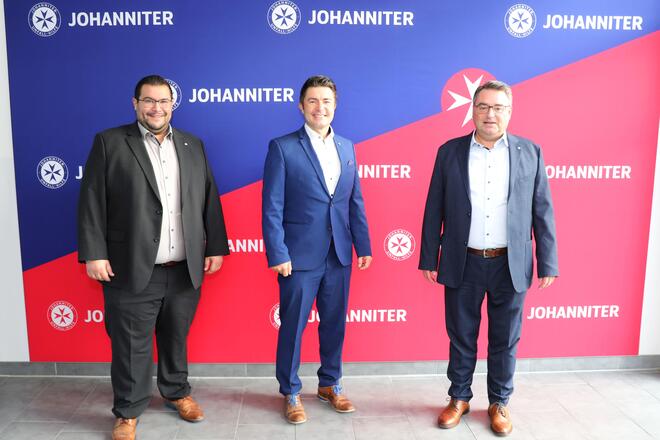 Vorstandsmitglieder Tobias Karl, rechts, und Martin Steinkirchner, links, Rahmen den scheidenden Pressesprecher der Johanniter Ostbayern, Andreas Denk