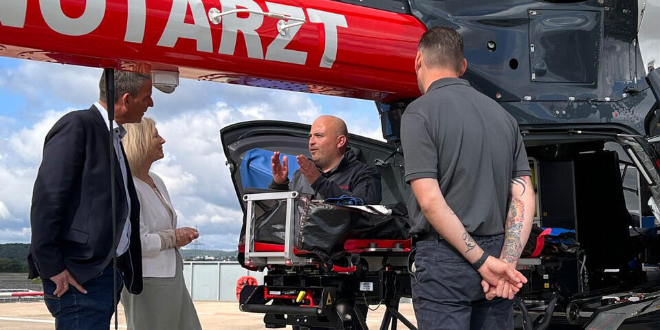 Landrätin Anita Schneider aus dem Landkreis Gießen und der Solmser Bürgermeister Frank Inderhal bekommen die Ausstattung und Möglichkeiten an einem Hubschrauber der JLR von Mitarbeitern erläutert.