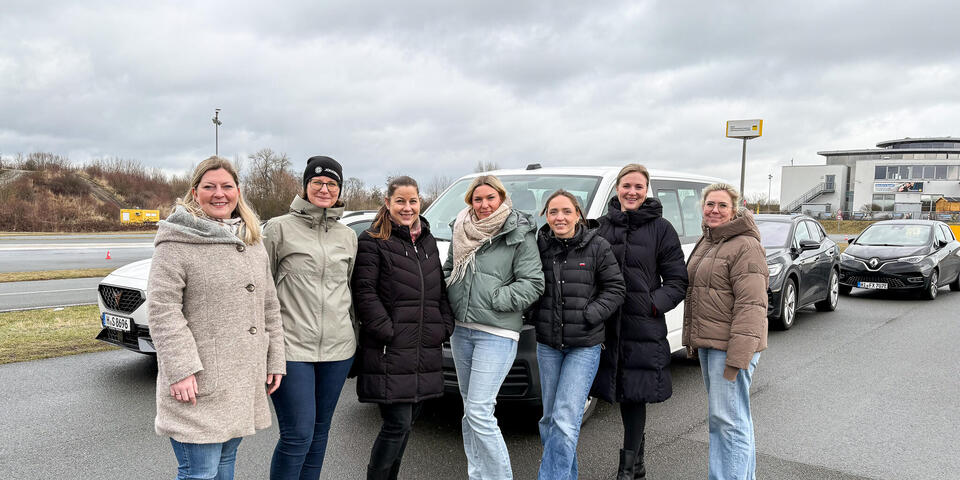 Sieben Frauen vor einem Auto.