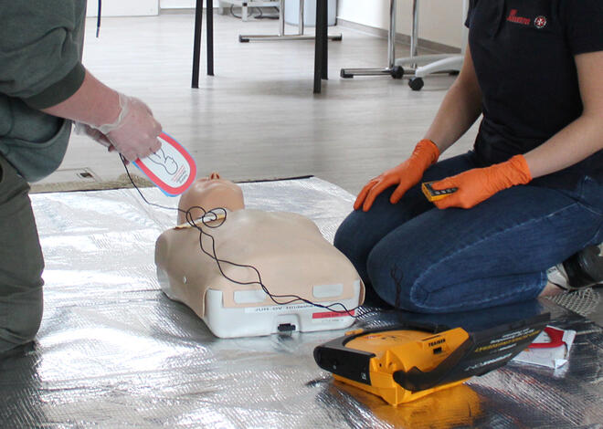 Man sieht wie jemand das AED anlegen möchte. 