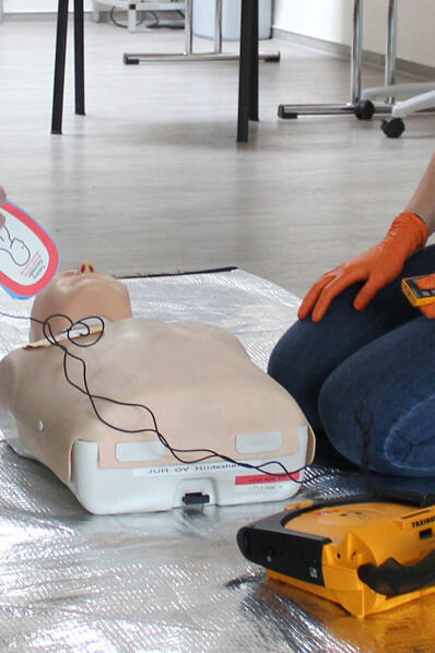 Man sieht wie jemand das AED anlegen möchte. 