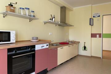 Eine Kinderküche mit Ofen, Mikrowelle, Spüle und Spülmaschine sowie Geschirr.