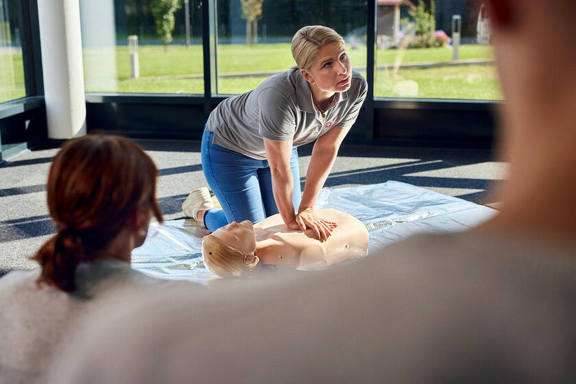 Frau demonstriert Herzmassage an Puppe im Erste-Hilfe-Kurs für Betreuungskräfte