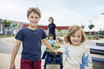 Kinder in einer Johanniter-Kita ziehen gemeinsam einen Wagen.