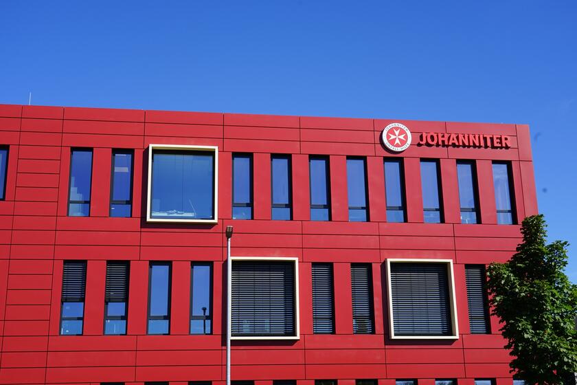 Man sieht ein großes, rotes Gebäude mit dem Schriftzug "Johanniter"