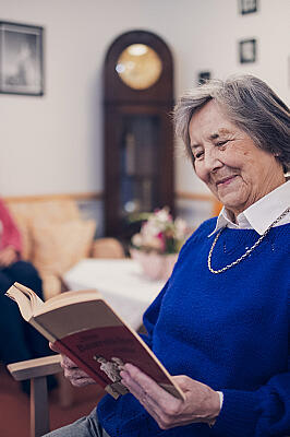Eine Bewohnerin in blauem Pullover liest