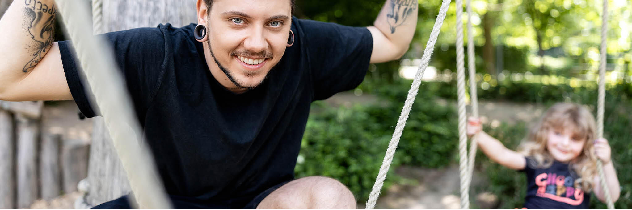 Ein Erzieher spielt mit einem Kind auf dem Spielplatz.