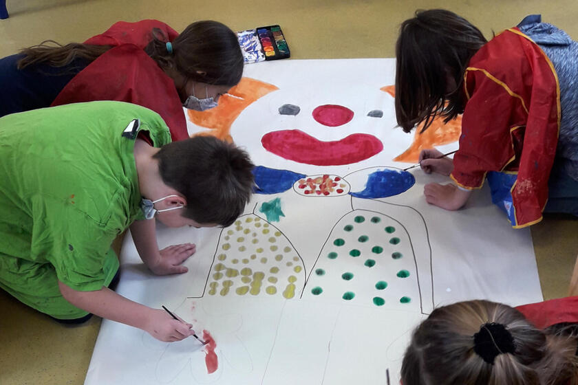 Kinder der Mittagsbetreuung malen in der Faschingszeit gemeinsam einen großen Clown.