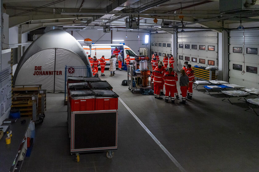 Behandlungsplatz 200 des Regionalverbandes Schleswig-Holstein Süd/Ost: aufgebaut in der Fahrzeughalle Lübeck. Der Behandlungsplatz besteht aus mehreren Großraumzelten, Sitzbänken, Rollwagen und Feldbetten.