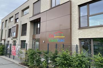 Der Eingangsbereich der Kita Kunterbunt mit Logo und Banner am Zaun.