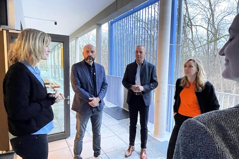 Fünf Personen beim Rundgang in der Lumi Natura sind ins Gespräch vertieft und stehen im Kreis vor dem Eingang der Einrichtung.