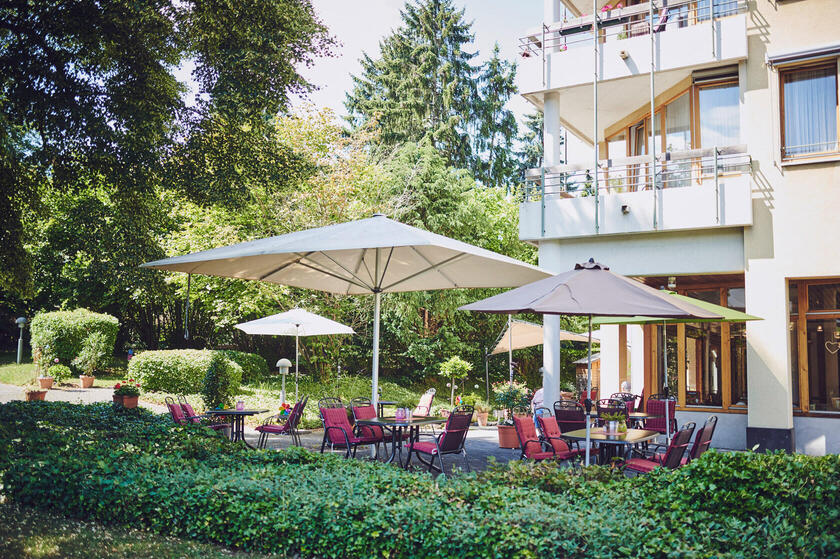 Sonnenschirme, Gartenmöbel mit roten Sitzauflagen im Außenbereich Johanniterhaus Sinzig