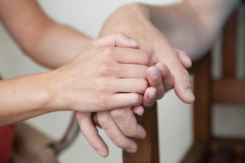 Pflegerin hält die Hand von einer Patientin.