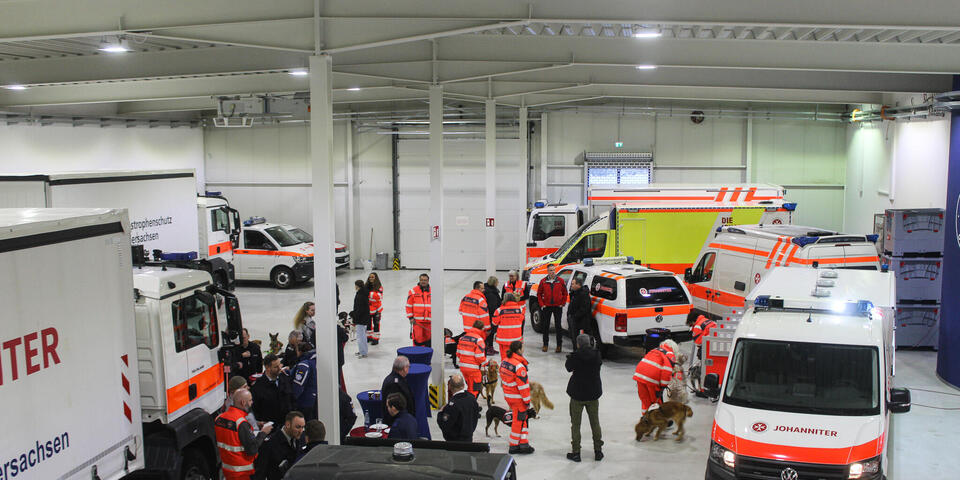 Blick von oben in eine Fahrzeughalle mit Einsatzfahrzeugen und Personen