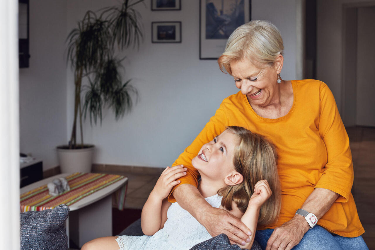 Eine Oma hält ihre Enkelin im Arm. Beide freuen sich.