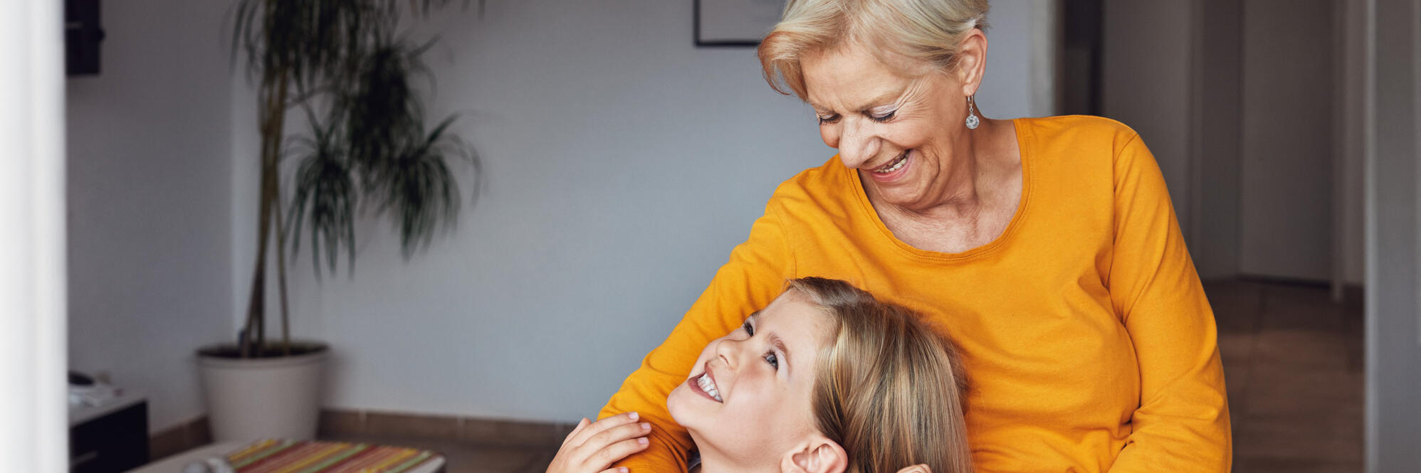 Eine Oma hält ihre Enkelin im Arm. Beide freuen sich.