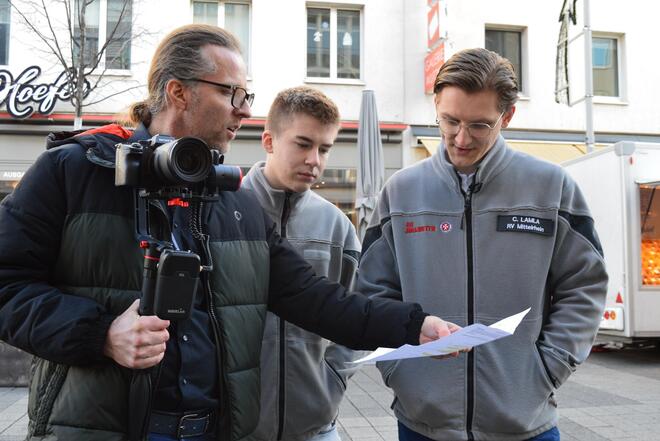 Ein Kameramann bespricht ein Drehskript mit zwei FSJlern