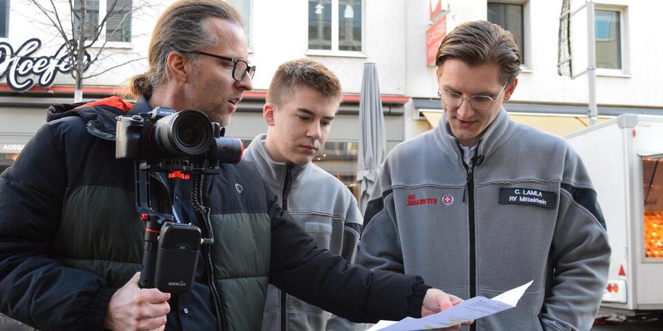 Ein Kameramann bespricht ein Drehskript mit zwei FSJlern