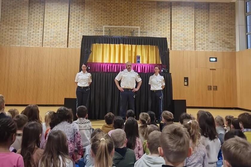 Die Kinder hören der Polizei aufmerksam zu.