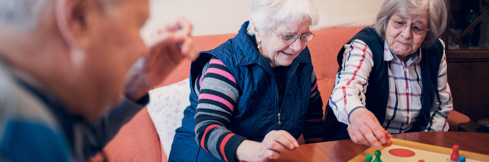 zwei Damen und ein Herr spielen Mensch-ärgere-dich-nicht