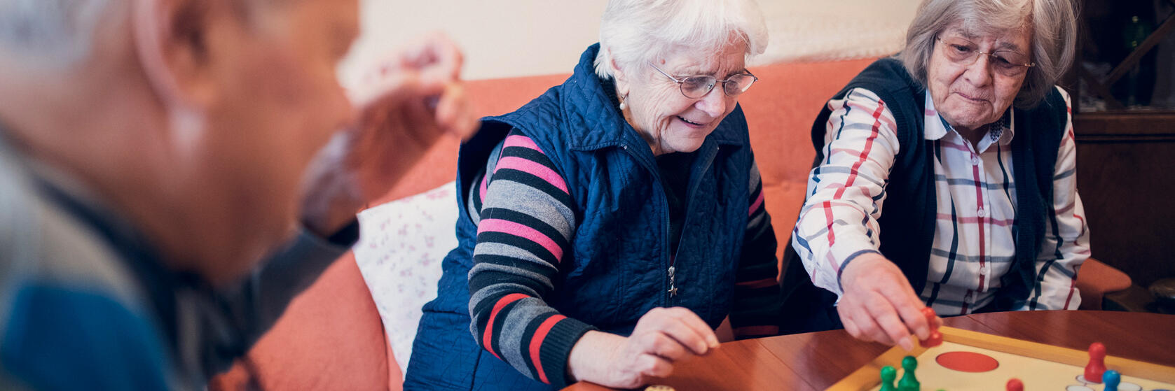 zwei Damen und ein Herr spielen Mensch-ärgere-dich-nicht