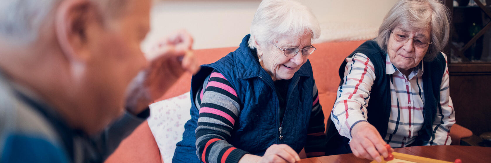 zwei Damen und ein Herr spielen Mensch-ärgere-dich-nicht