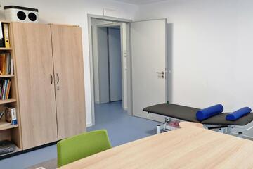 Bild vom Therapieraum der Ergotherapie mit Therapiematerial und Behandlungsliege