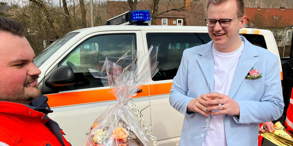 Ein Johanniter überreicht einem Mann im Anzug einen Geschenkkorb