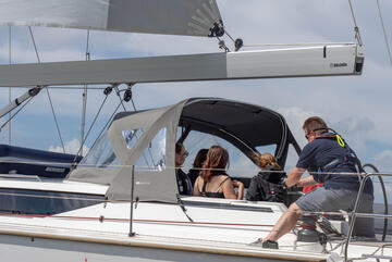 Ein Crewmitglied auf dem Segelboot bedient die Winsch, um ein Segel zu setzen.