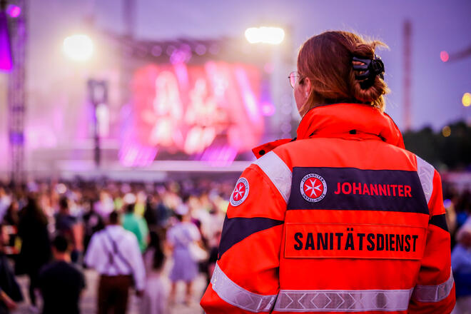 Eine Einsatzkraft des Johanniter-Sanitätsdienstes steht vor einer Bühne.
