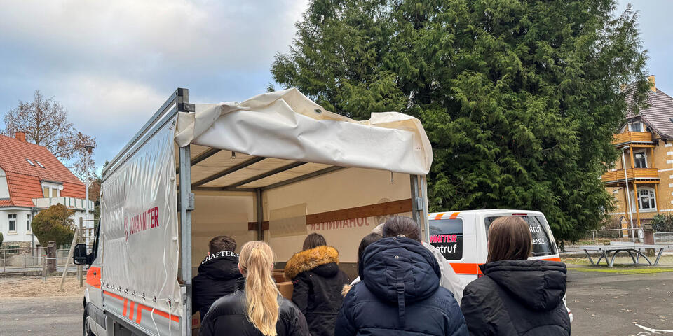Kinder beladen einen LKW mit Paketen. 