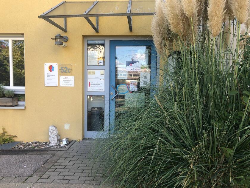 Die Eingangstür zum Mehrgenerationenhaus mit einem großen Busch an der Seite.