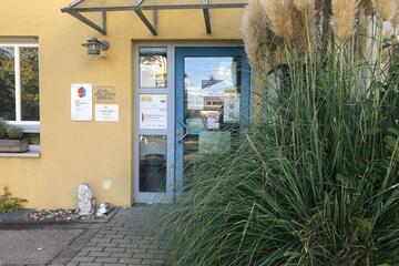 Die Eingangstür zum Mehrgenerationenhaus mit einem großen Busch an der Seite.