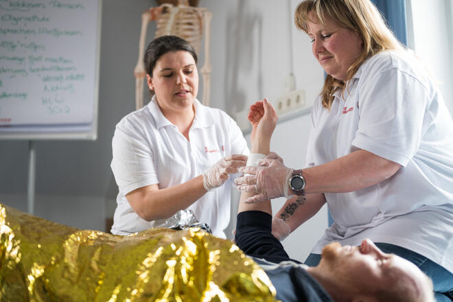 Praxisübung in der Betriebssanitäterausbildung: Verband an Arm wird angelegt.