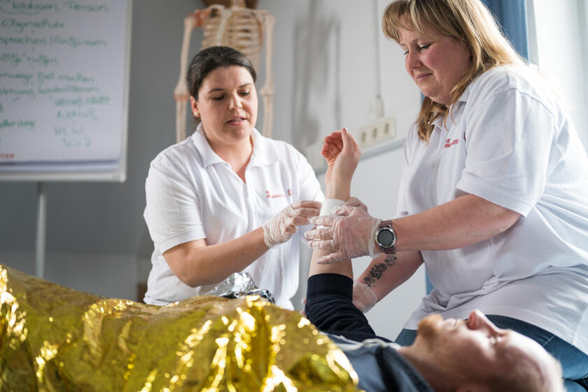 Praxisübung in der Betriebssanitäterausbildung: Verband an Arm wird angelegt.