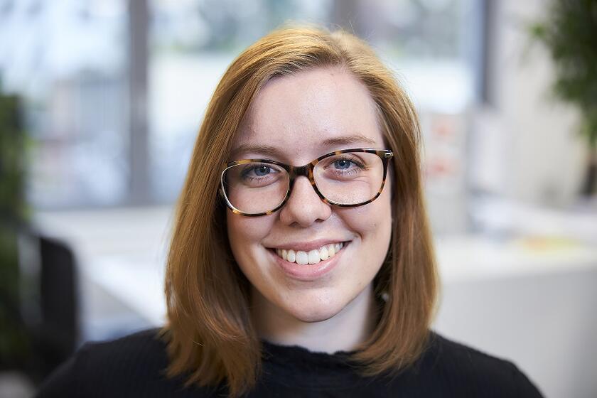 Eine junge Frau mit Brille lächelt in die Kamera