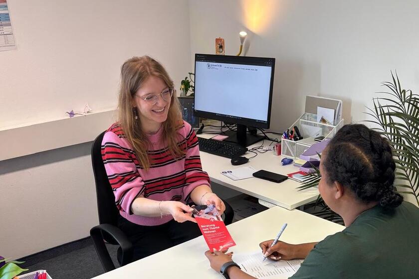 Mitarbeiterin übergibt Flyer.