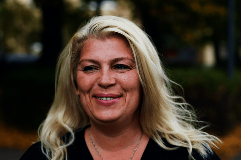 Kopfporträt einer blonden, lächelnden Frau mit offenen Haaren