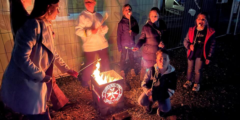 Kinder stehen an einer Feuerschale