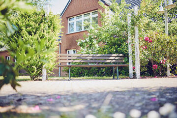 Gartenbank zwischen zwei kleinen Bäumen laden zum Entspannen ein