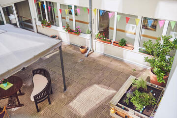 Angelegte Blumen-, Planzkästen und Gartenmöbel im Innenhof laden zum Treffen im Johanniter-Stift Köln Ehrenfeld.