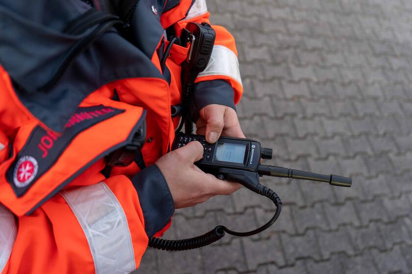 Ein Johanniter aus Wiesbaden hält ein Digitalfunkgerät in der Hand.